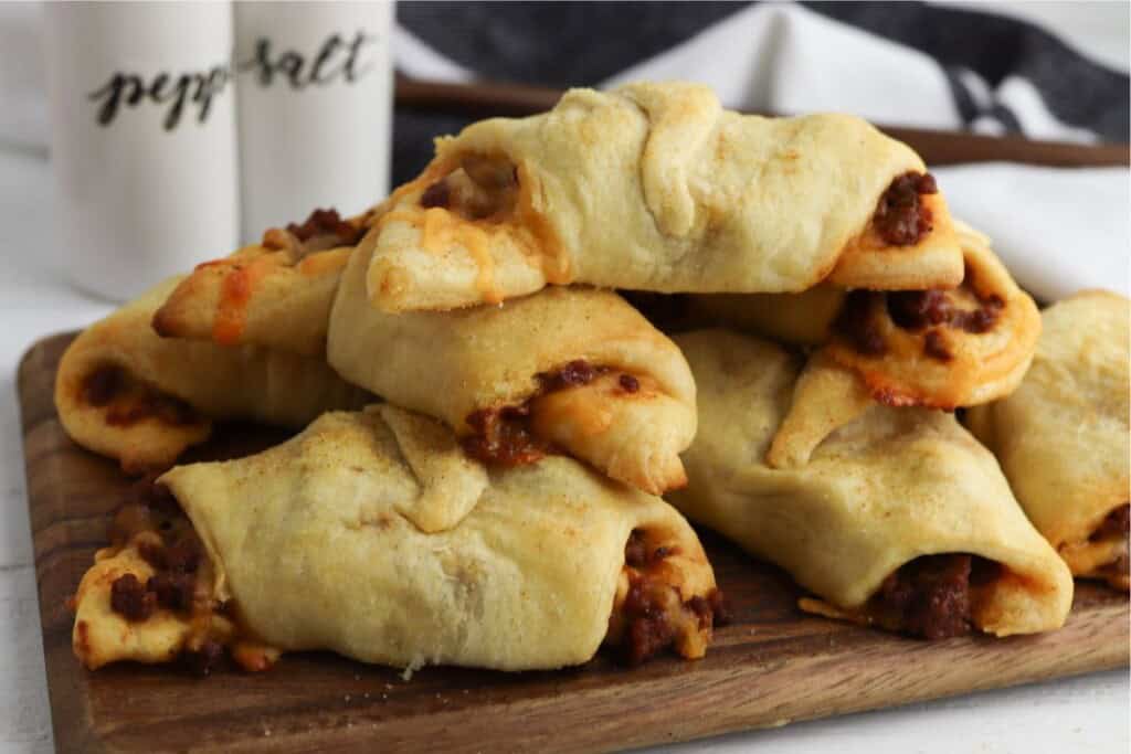 Crescent roll sloppy joes on a cutting board with salt and pepper shakers behind them