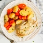 Overhead view of chicken, potatoes and carrots on a white plate.