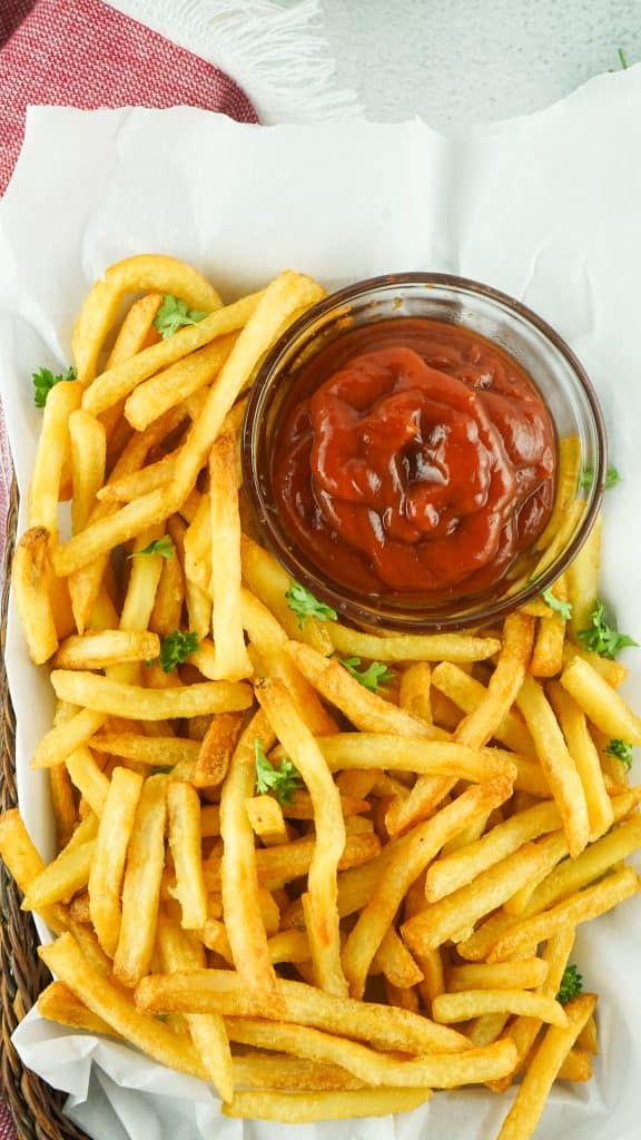 Ovehead view of Ore-Idea French fries cooked in the air fryer with a b owl of ketchup.