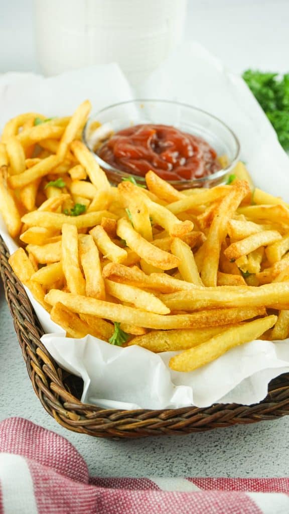 Golden Ore-Ida French fries with a bowl of ketchup in a basket.