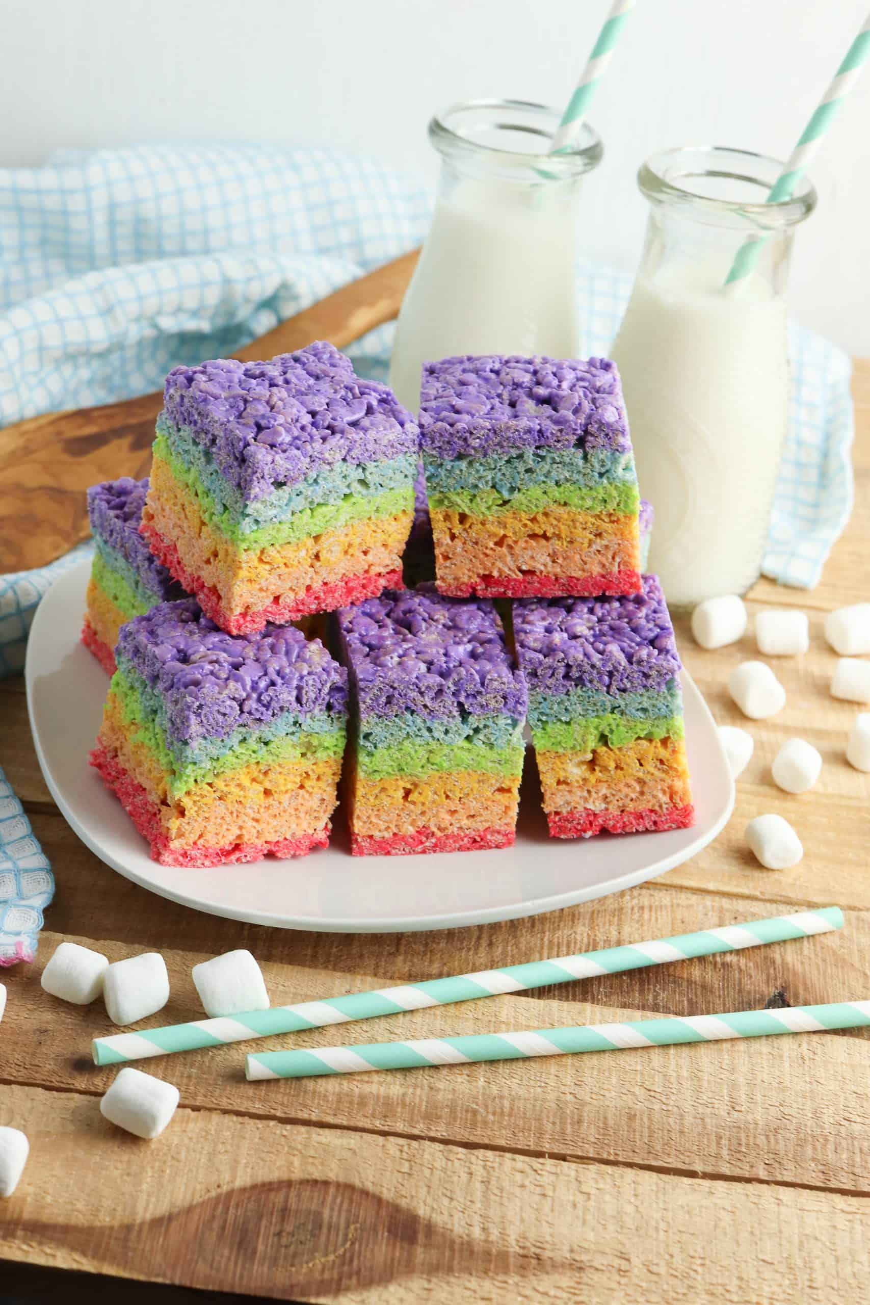 Rainbow treats on a white plate with milk behind it.