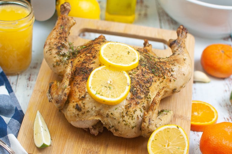 Air fryer butterfly chicken with lemon slices on top of it.