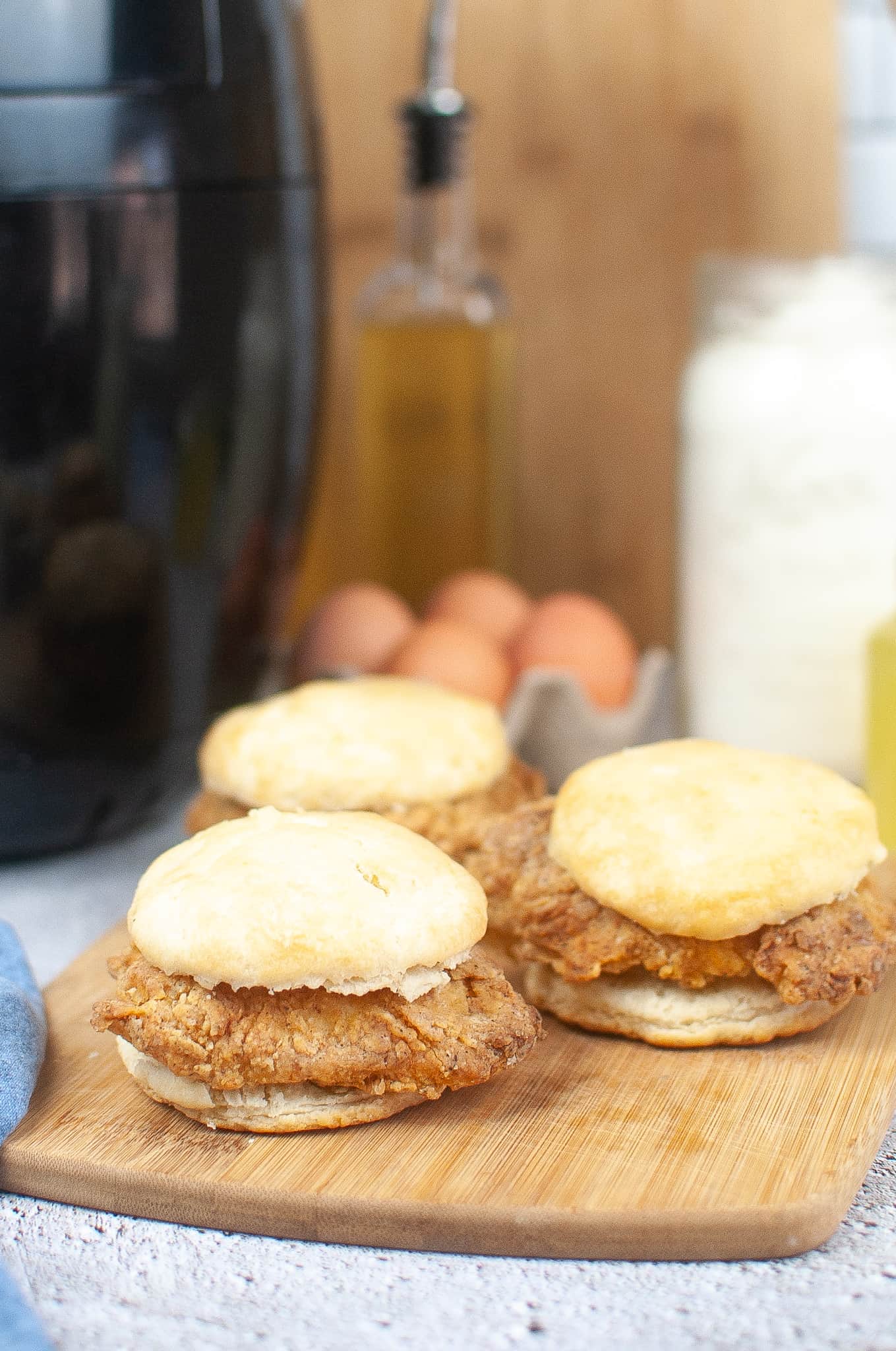 3 Air Fryer Chicken Biscuit Sandwiches on a cutting board.
