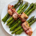 Bacon asparagus with sea salt on a white plate with an overhead view.