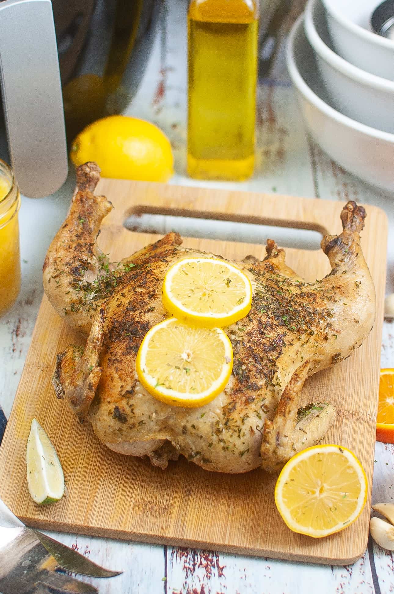 Chicken with lemon slices on a wooden cutting board.