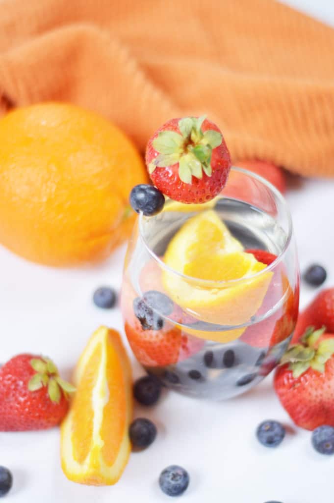 Angled view of orange-infused spa water with berries and orange slices.