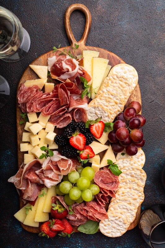 Charcuterie arranged on a wooden board.