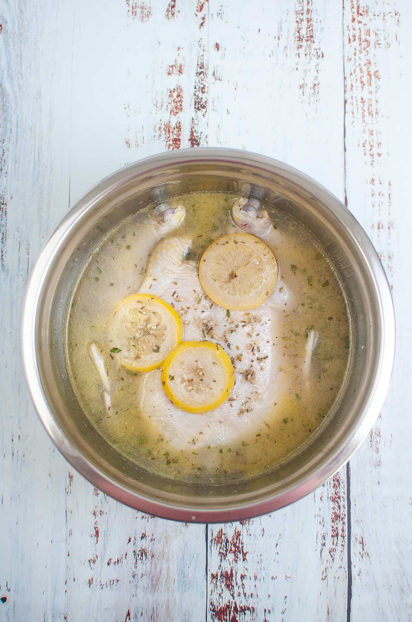 Overhead view of a whole chicken in citrus marinade.