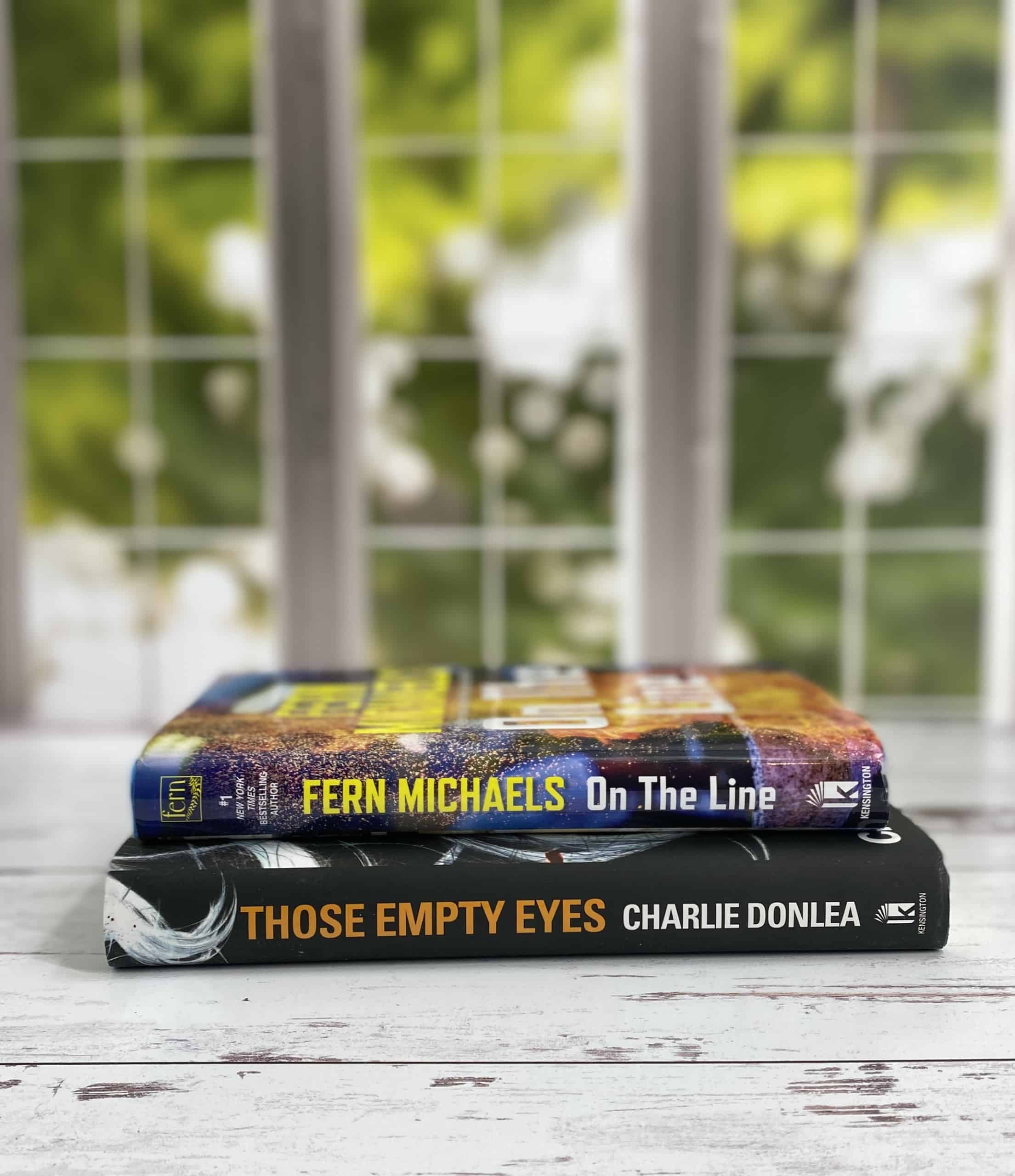 Kensington books in front of a window with Spring themed green trees in the background.