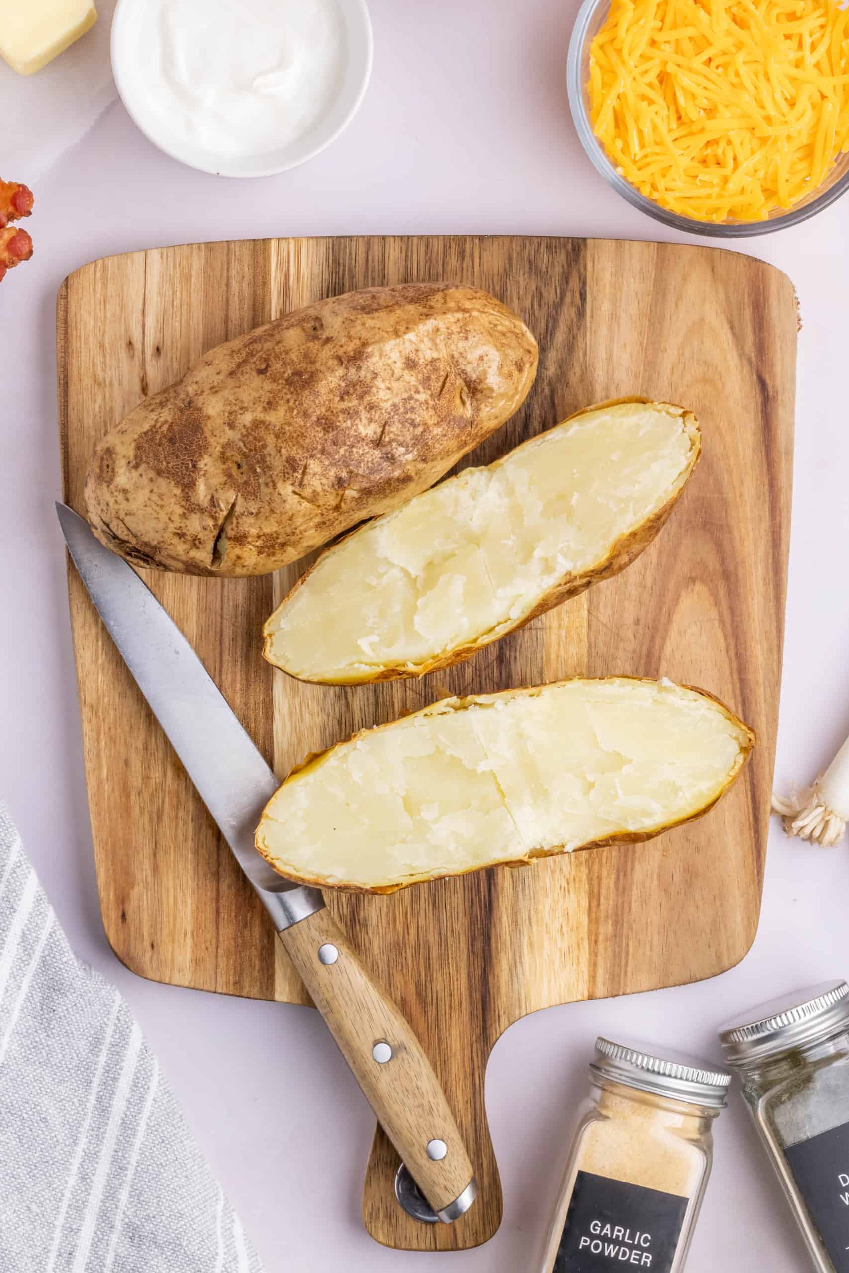 Baked potatoes on a wooden cutting board.