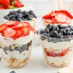 2 mixed berry mini trifles, one topped with strawberries and one topped with blueberries.