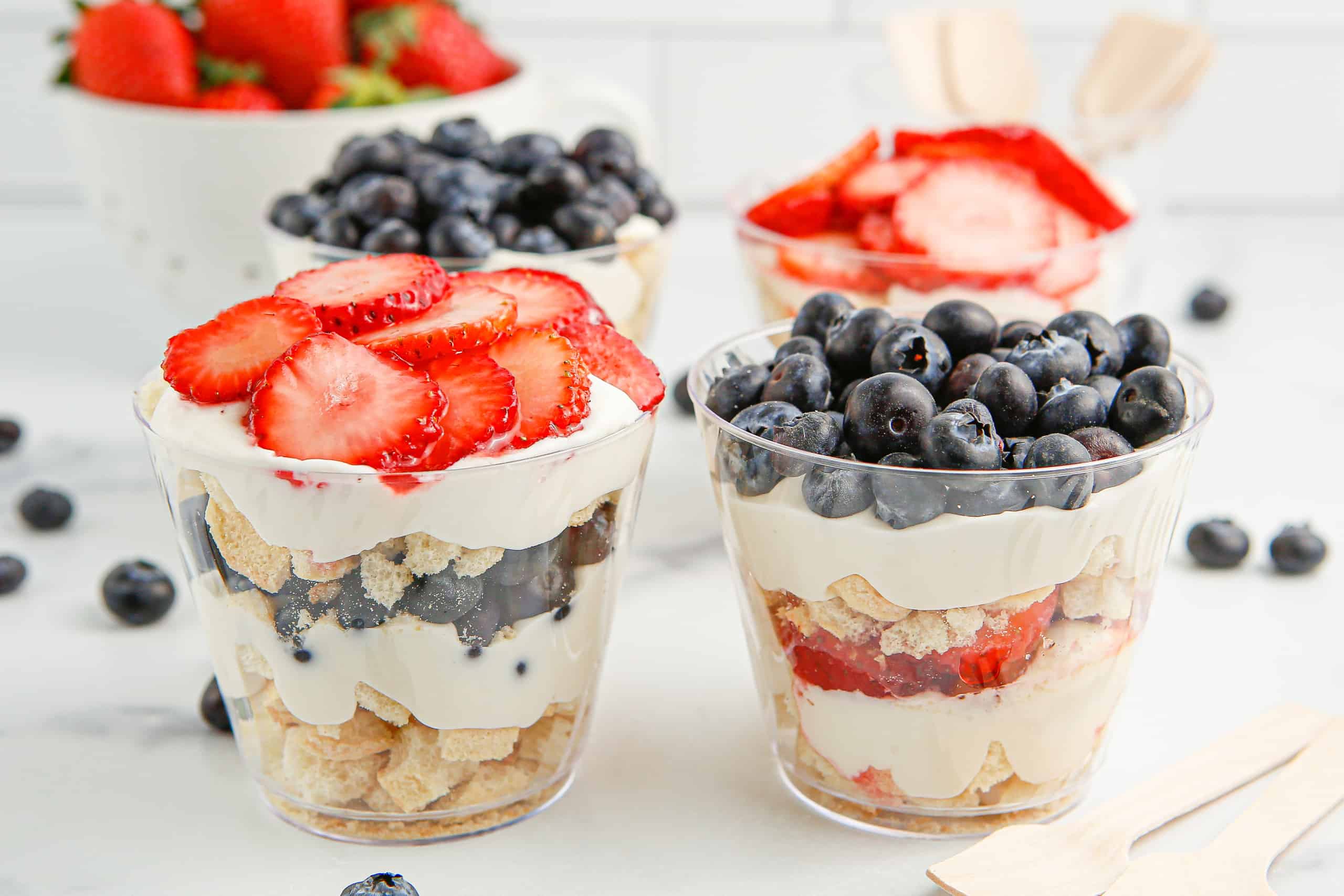 2 mixed berry mini trifles, one topped with strawberries and one topped with blueberries.