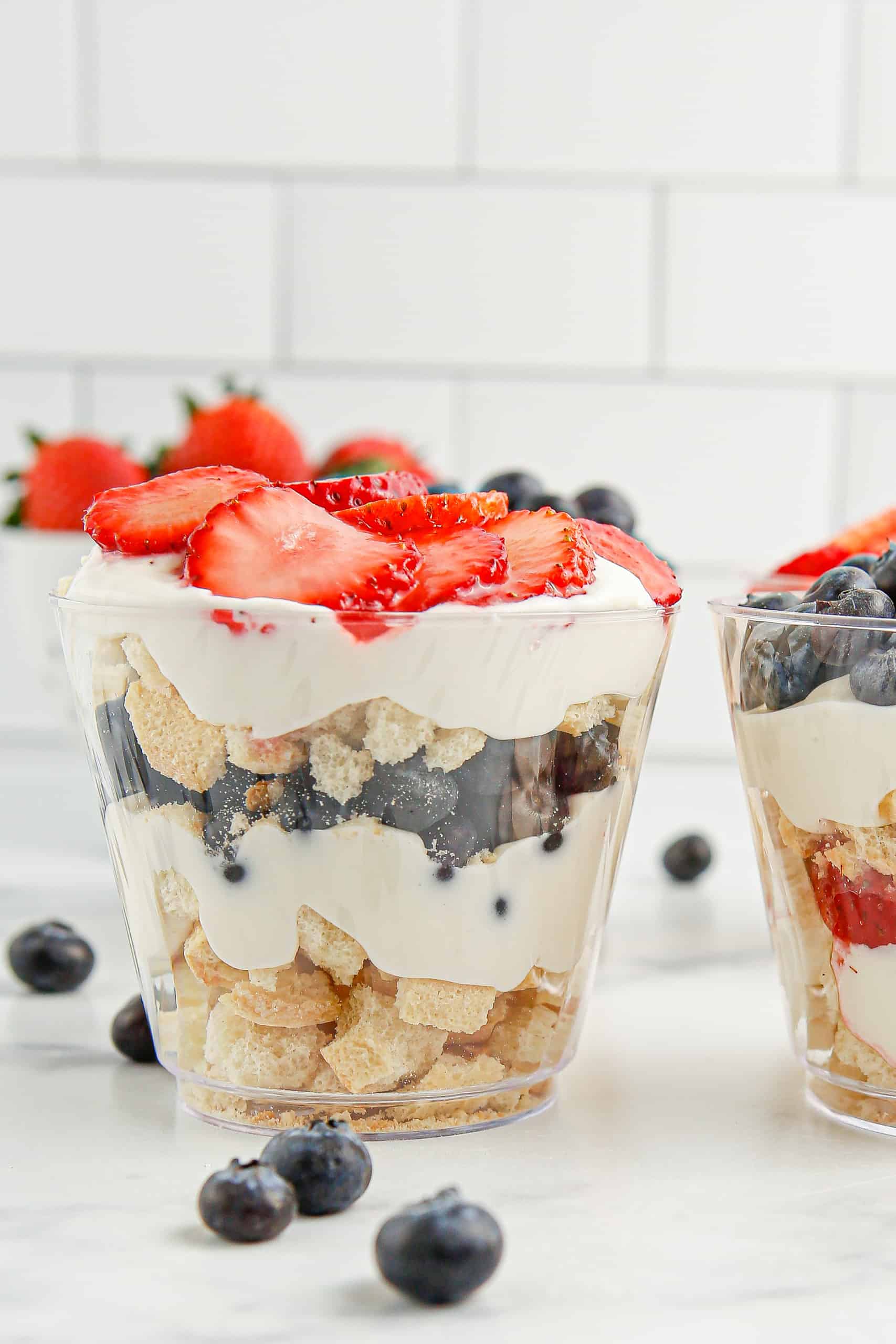 Mini trifle in a plastic cup with strawberries on top.