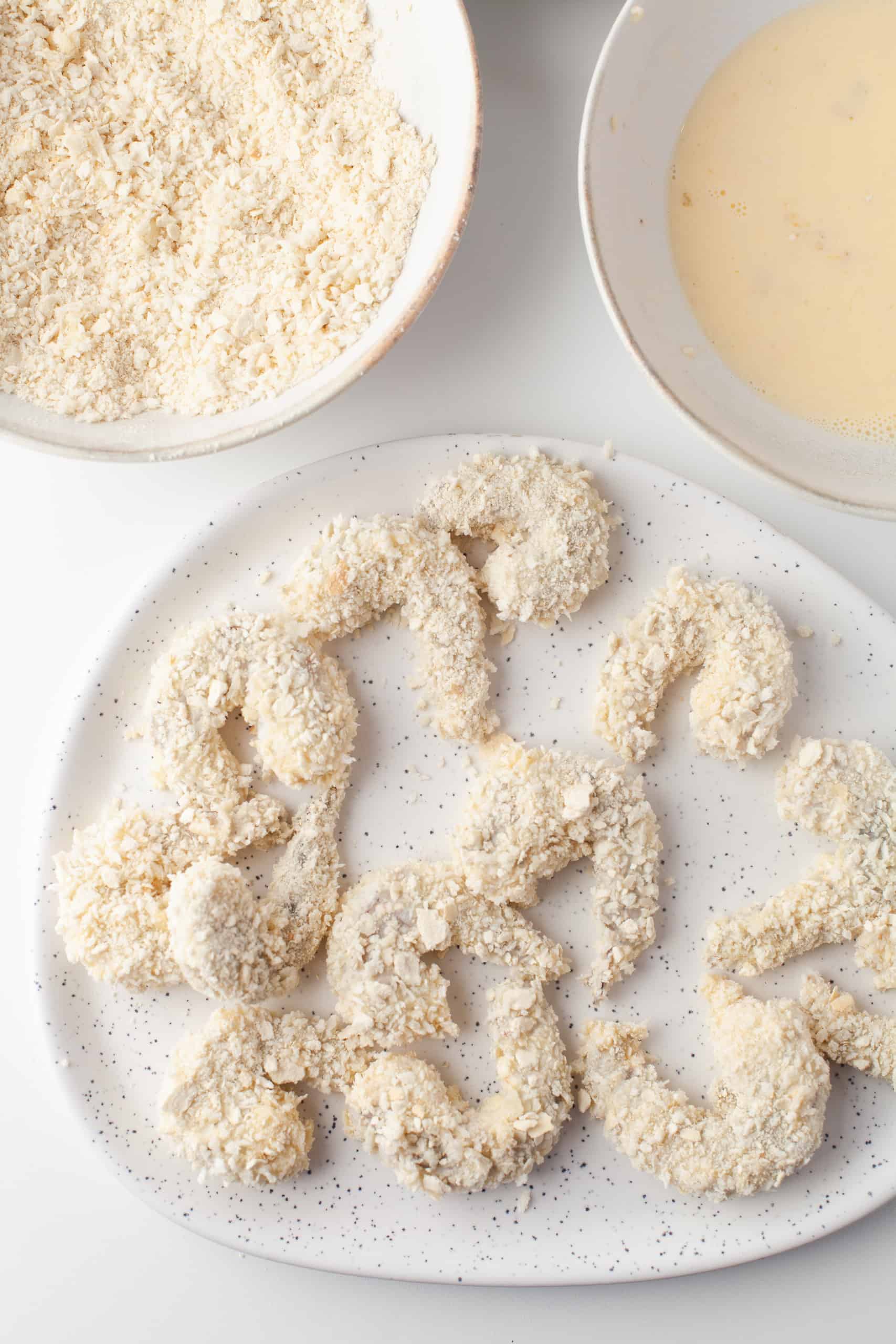 Overhead view of breaded shrimp on a white plate.