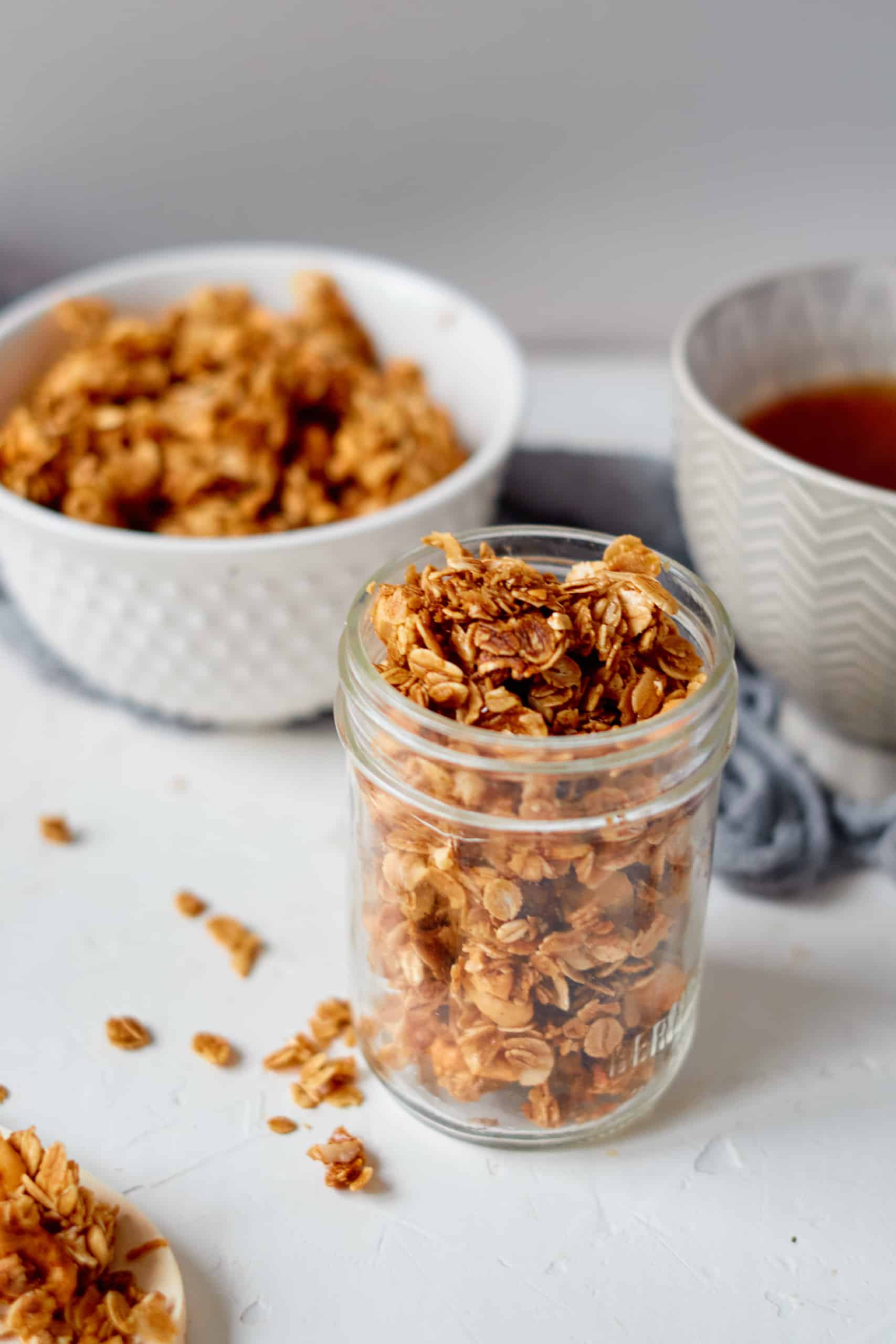 Pumpkin granola in a Mason jar and in a white bowl.