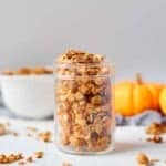 Pumpkin spice granola in a Mason jar with mini pumpkins and a bowlof granola behind it.