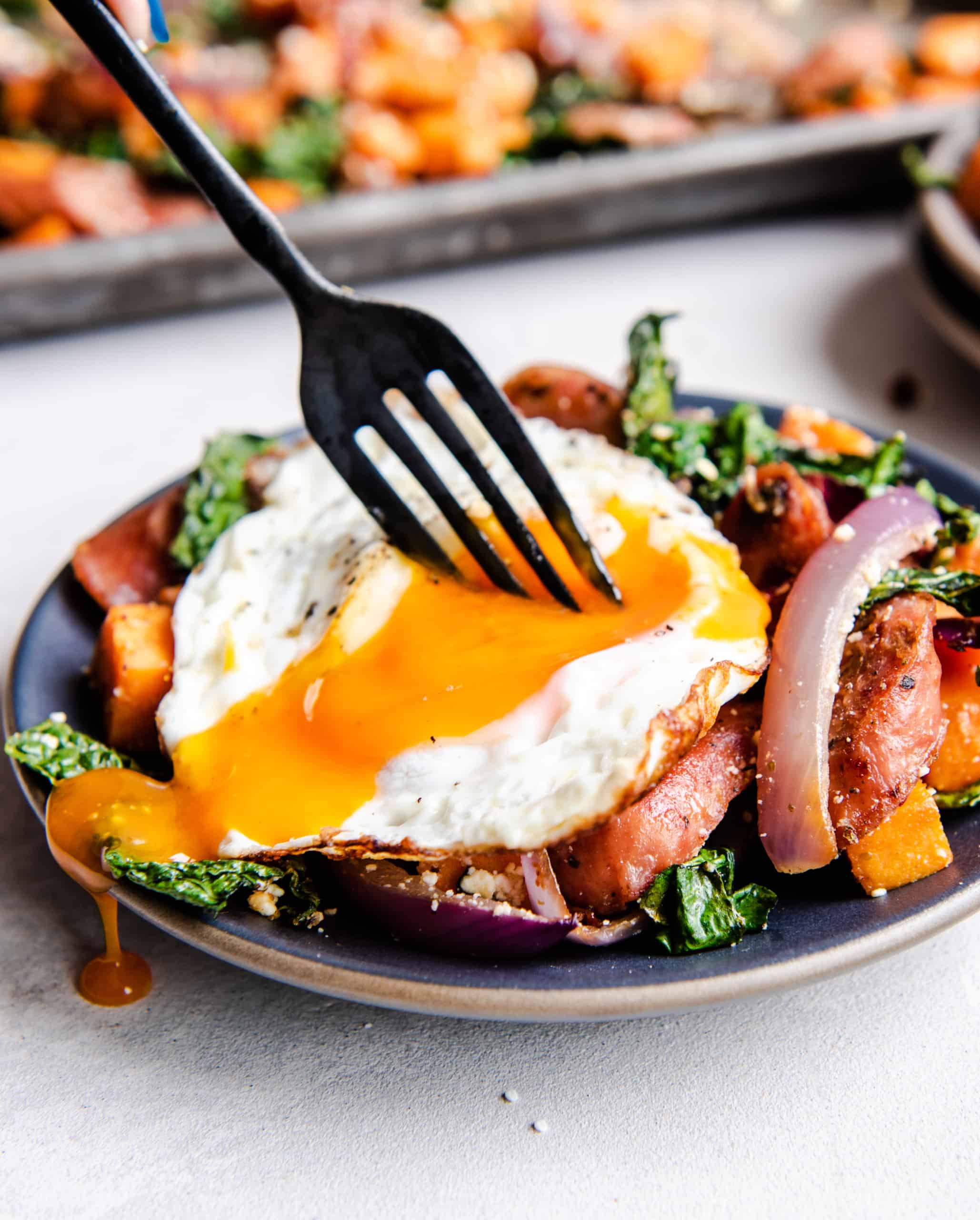 Fork in a poached egg over sweet potato hash.