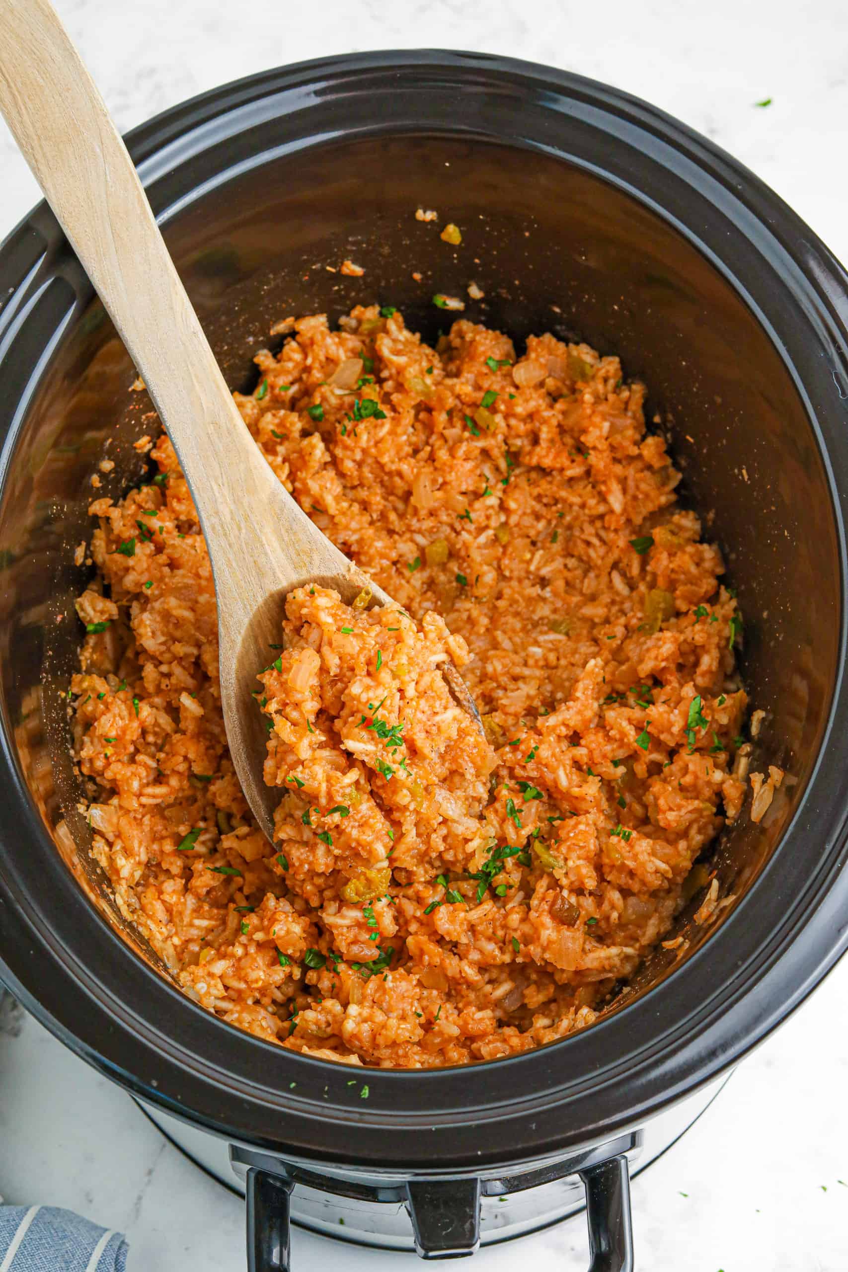 A spoonful of Spanish rice in a crockpot.
