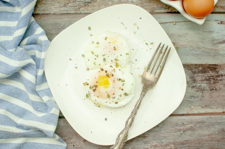 Overhead view of poached egg on a wite plate.