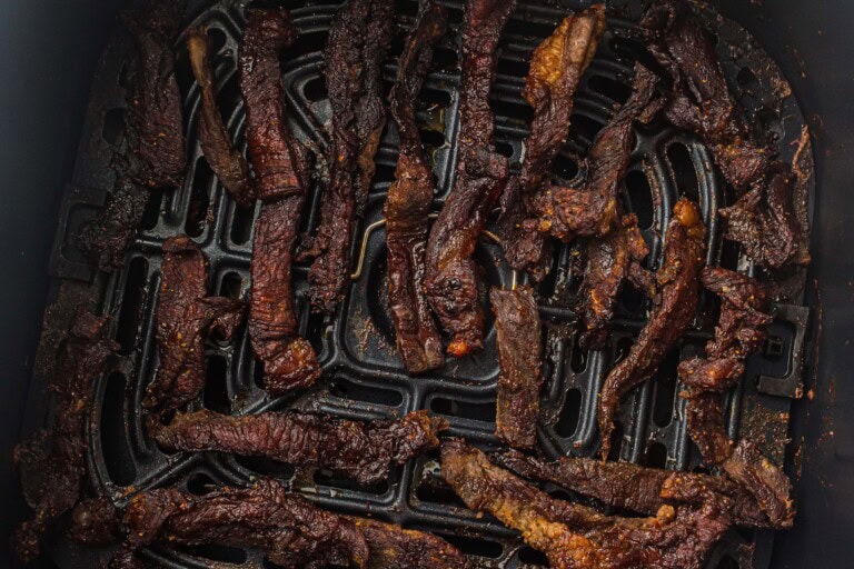 Overhead view of beef jerky in an air fryer basket.