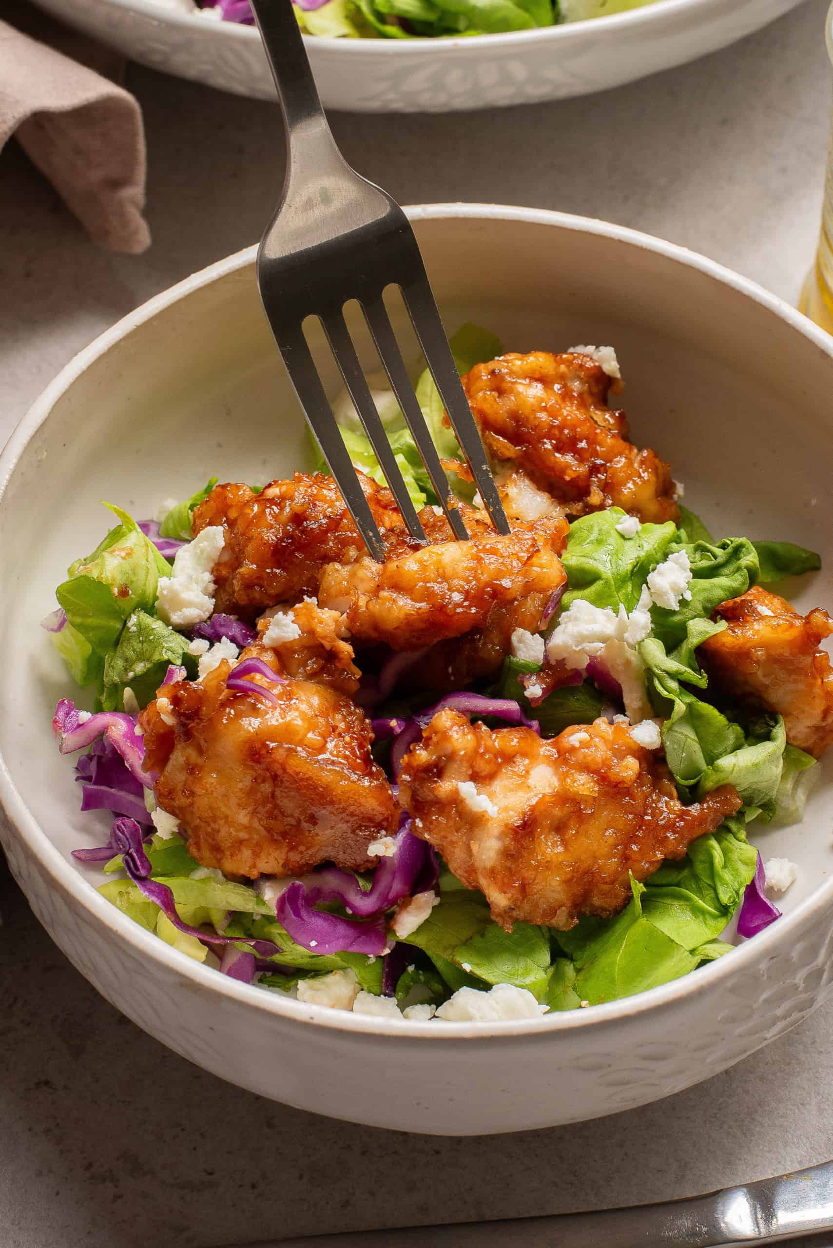 Bowl of salad with BBQ chicken pieces.