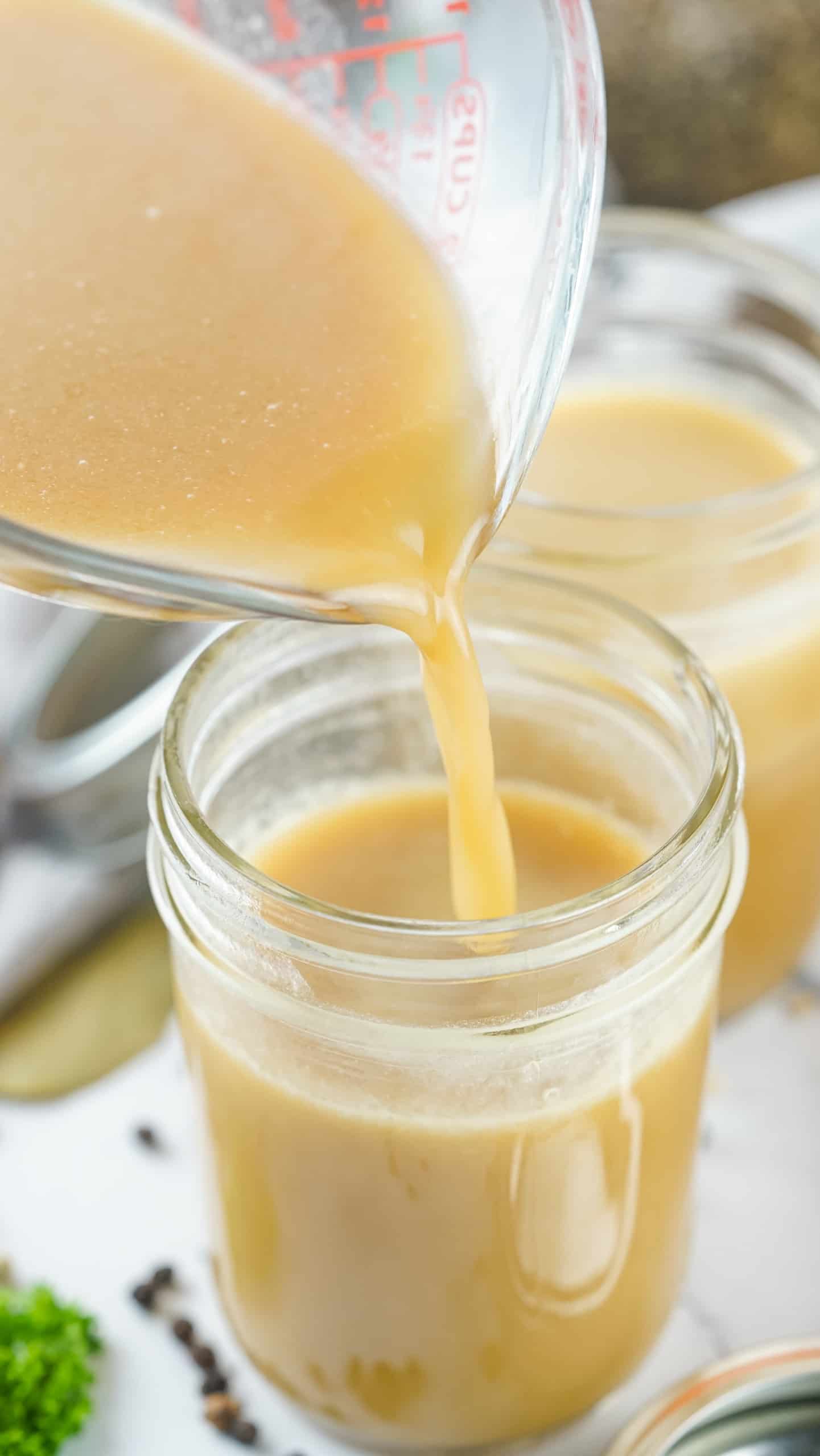 Pouring the chicken stock in Mason jars.
