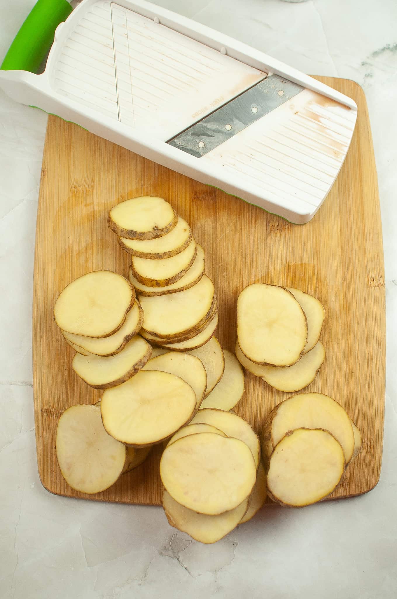 Sliced potatoes in a cutting board.