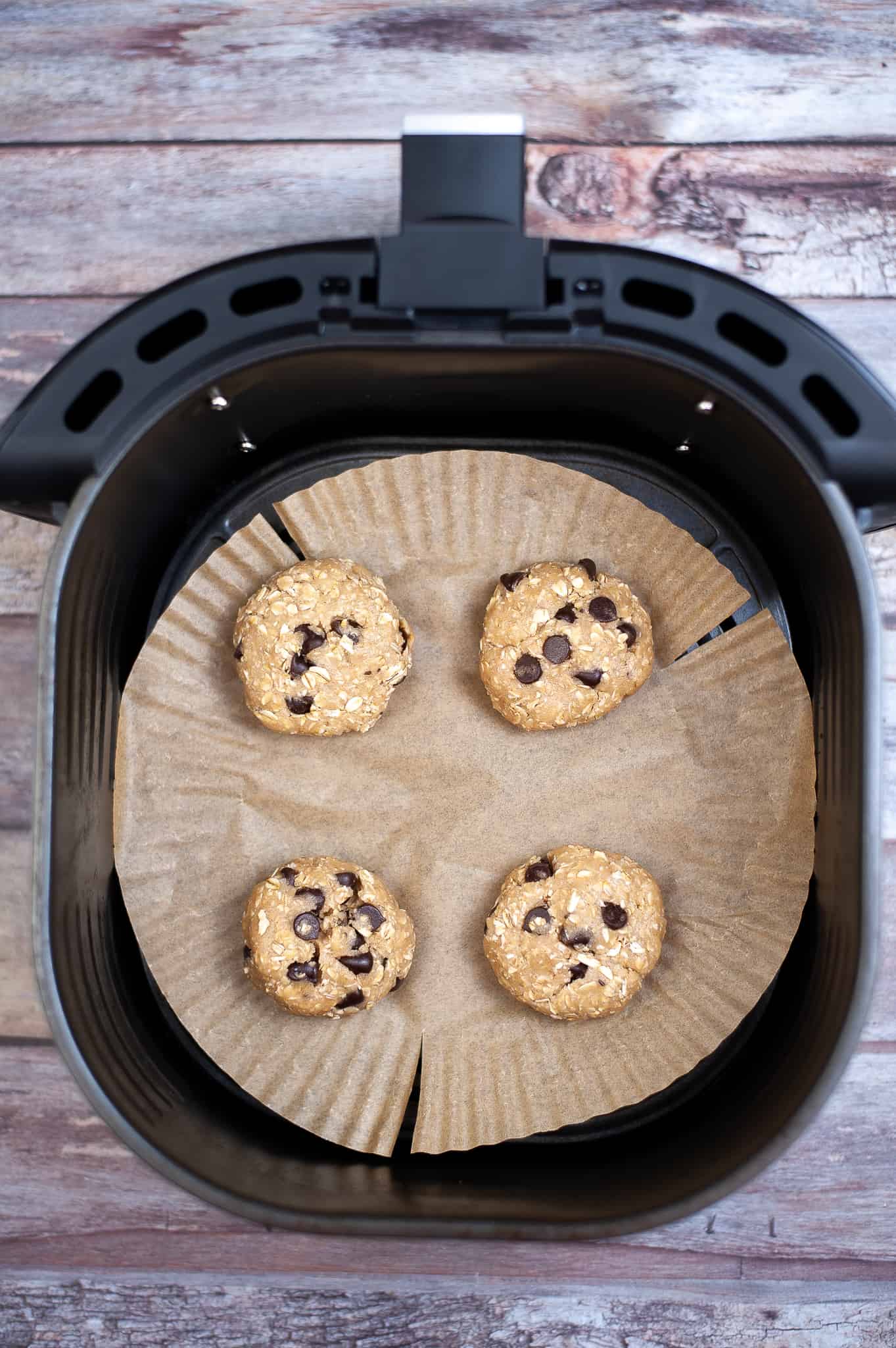 Overhead view of cookie dough balls in air fryer basket.