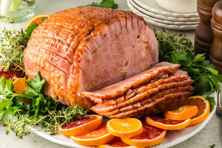 Sliced ham on a platter garnished with orange slices.