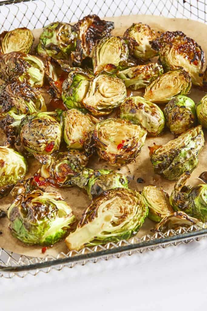 Overhead view of sweet chili Brussels sprouts in an air fryer basket.