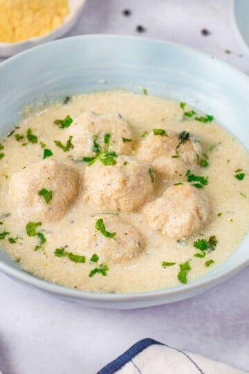 Chicken Alfredo Meatballs garnished with parsley in a light blue bowl.
