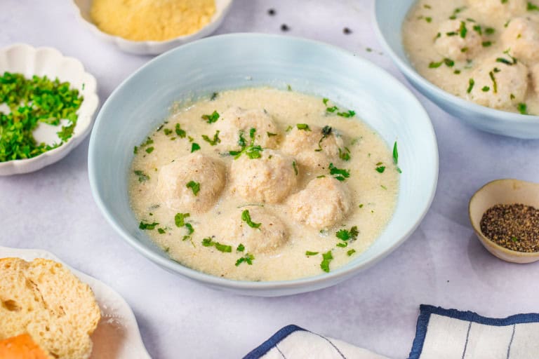 Chicken Alfredo Meatballs garnished with parsley in a light blue bowl.