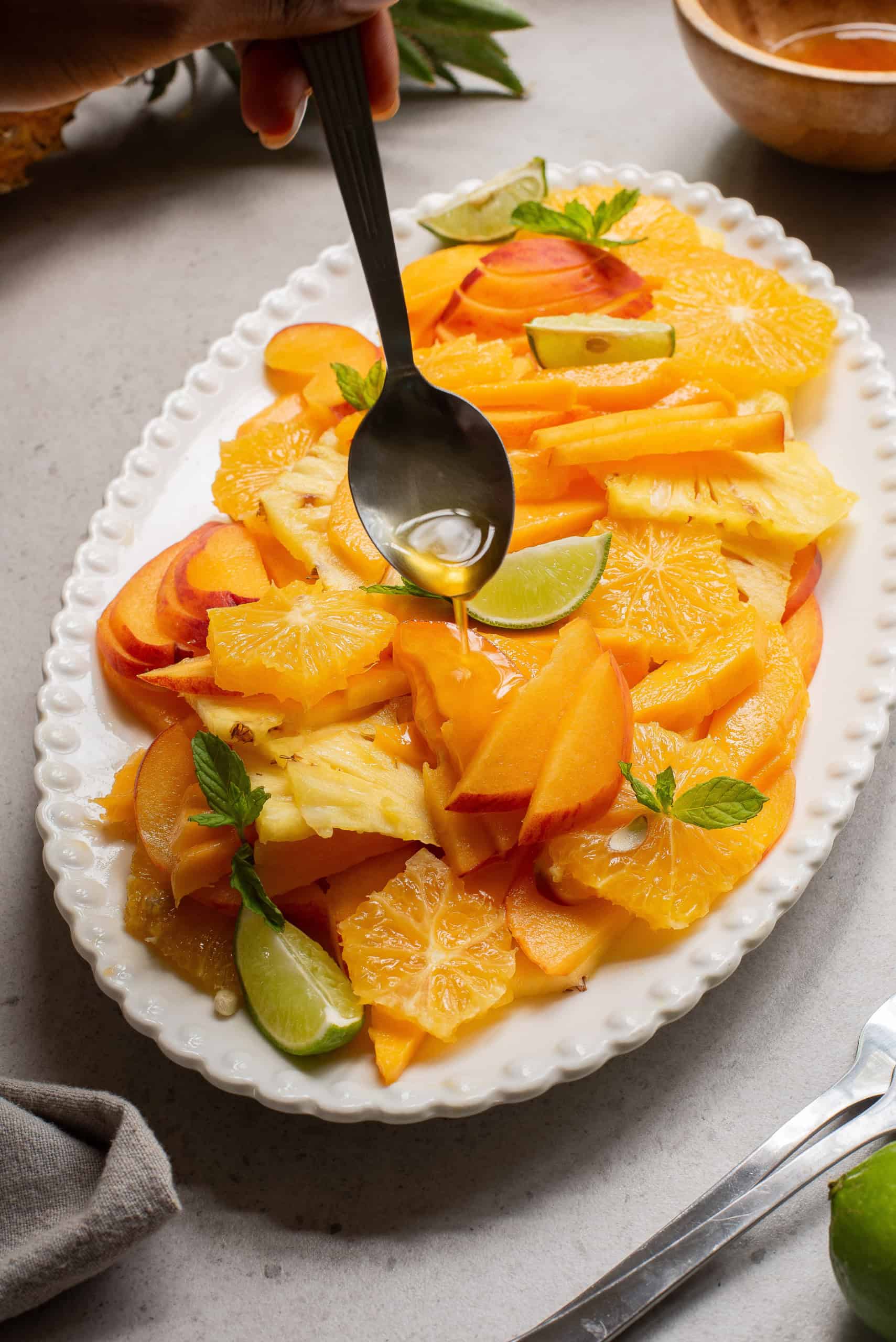 Overhead view of drizzling dressing over fruit salad.