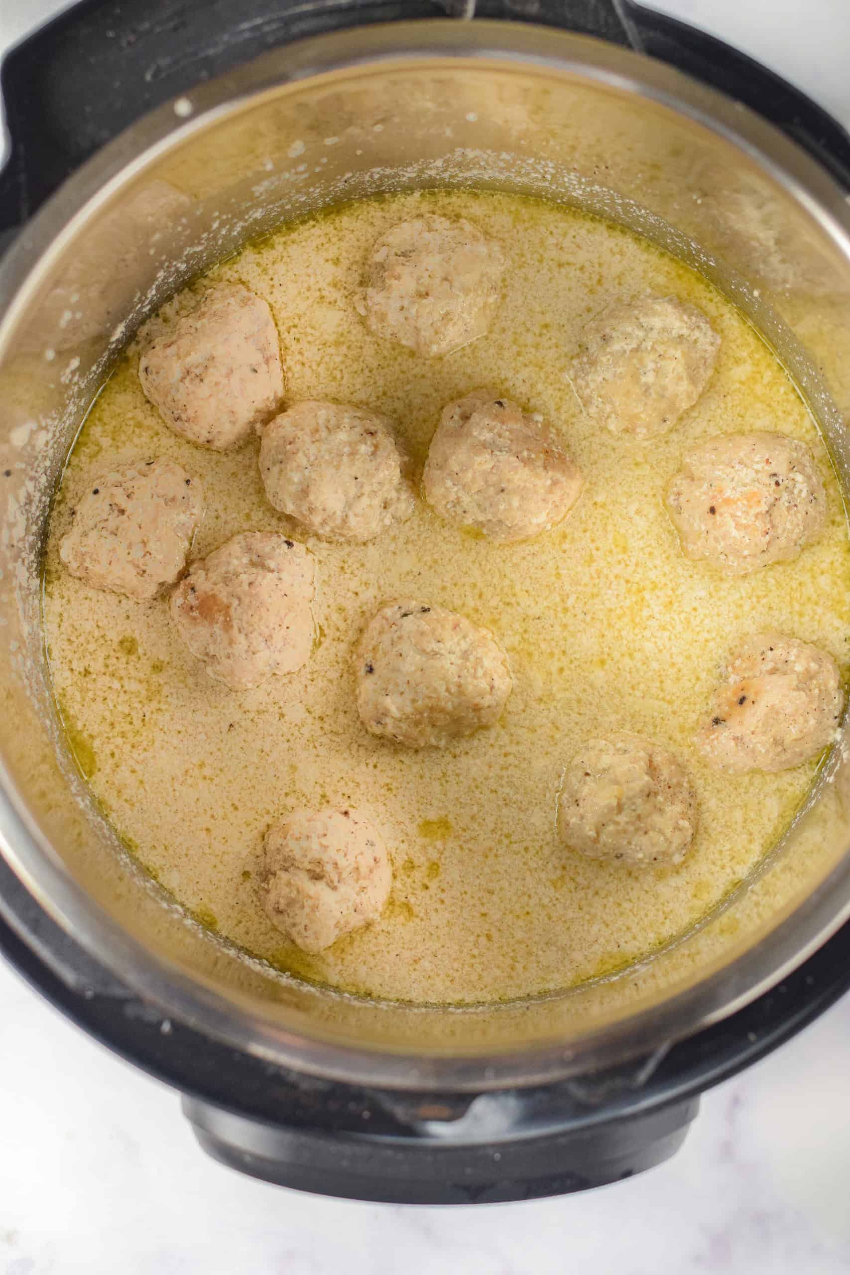 Overhead view of chicken meatballs in alfredo sauce in Instant Pot.