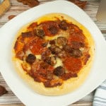 Overhead view of pizza with pepperoni and sausage and bacon.