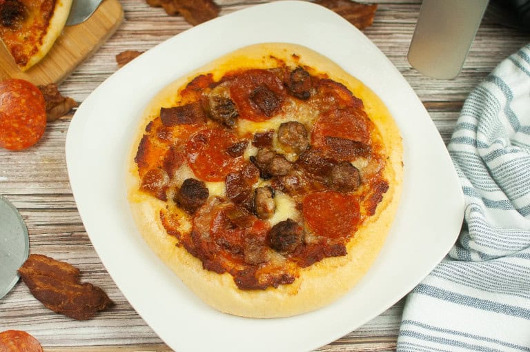 Overhead view of pizza with pepperoni and sausage and bacon.