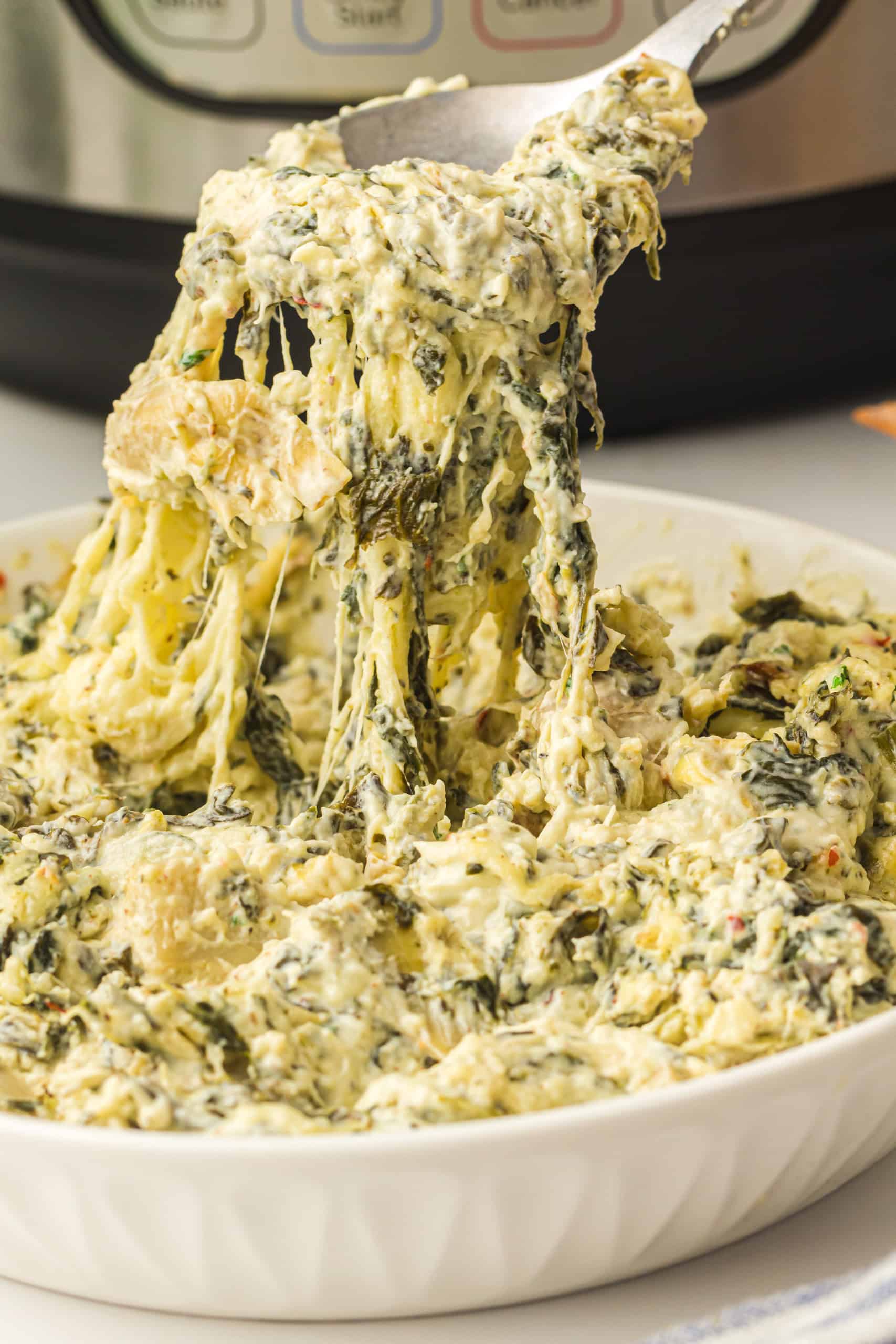 Cheese pull on a spoon of spinach artichoke Instant Pot dip.