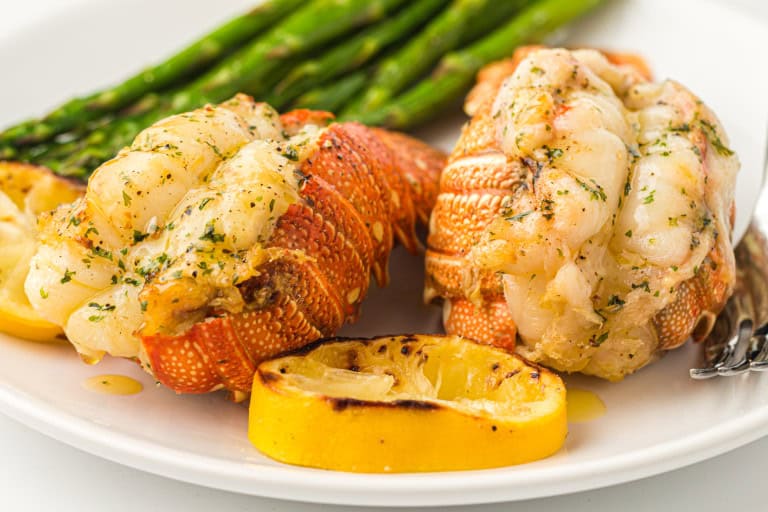 Air Fryer Lobster tails with asparagus on a white plate.