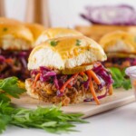 Head on view o pulled pork sliders with purple cabbage slaw.