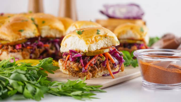 Head on view o pulled pork sliders with purple cabbage slaw.
