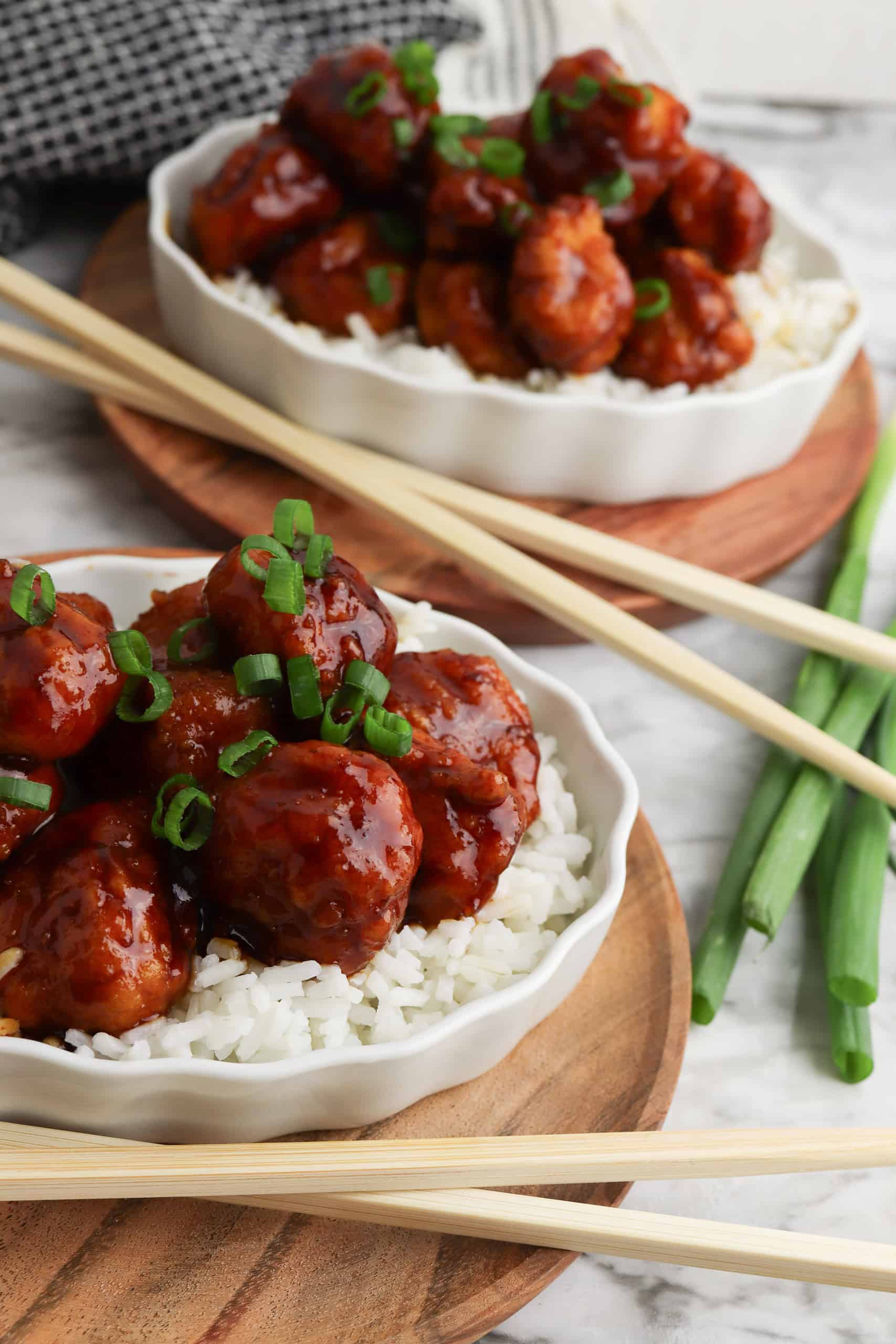2 white plates with air fryer General Tso's chicken over white rice with chopsticks on the side.