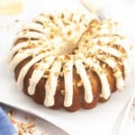 Carrot Cake Bundt Cake with Cream Cheese Frosting and chopped pecans on top of cake.