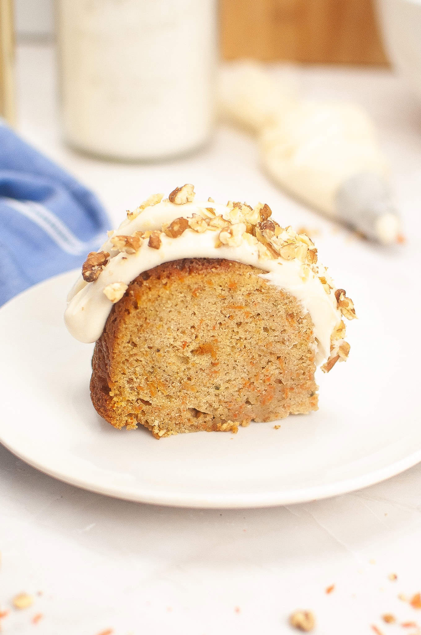 Head on view of slice of Carrot cake with cream cheese frosting on a white plate.