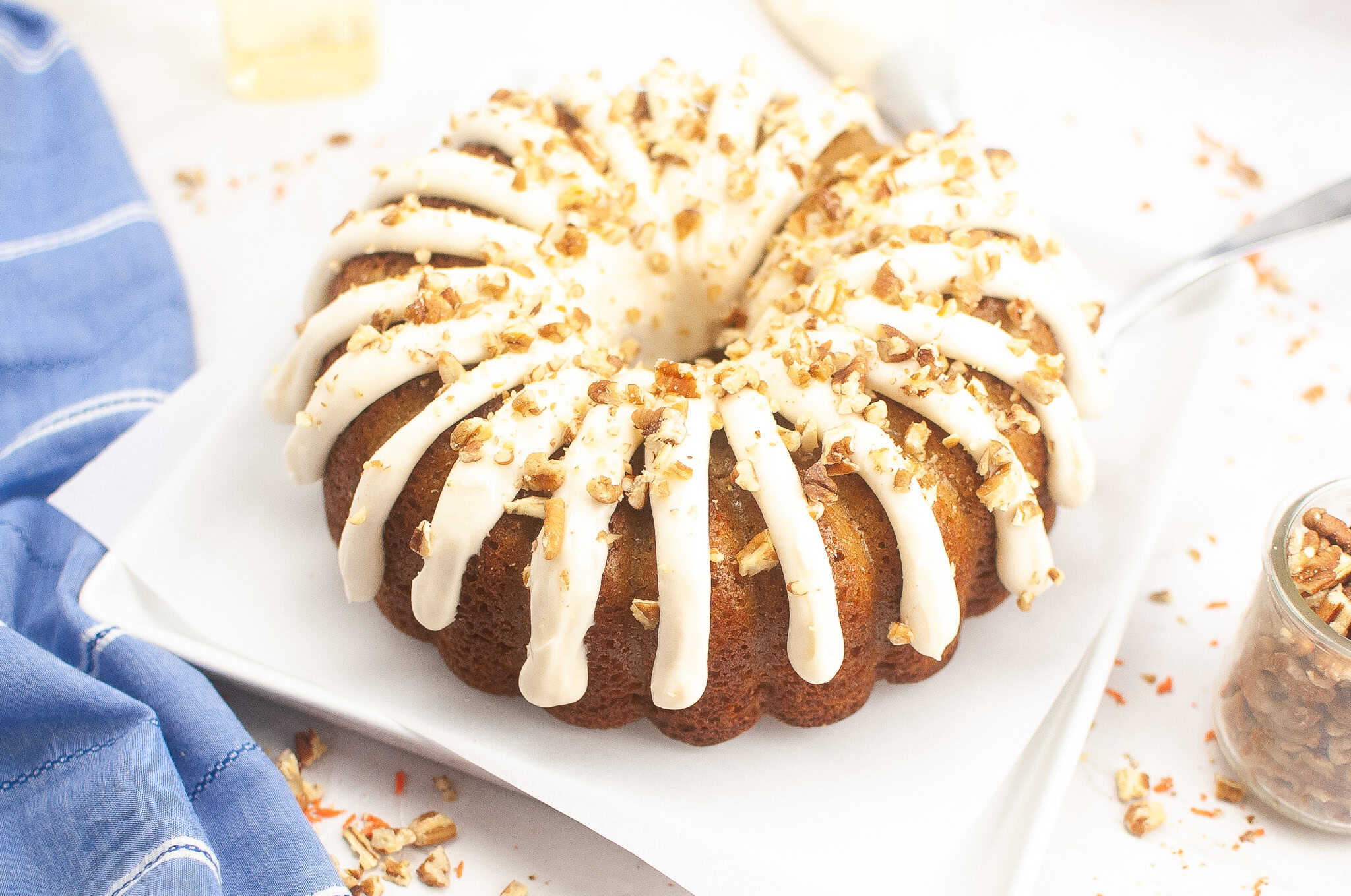 Carrot Cake Bundt Cake with Cream Cheese Frosting and chopped pecans on top of cake.