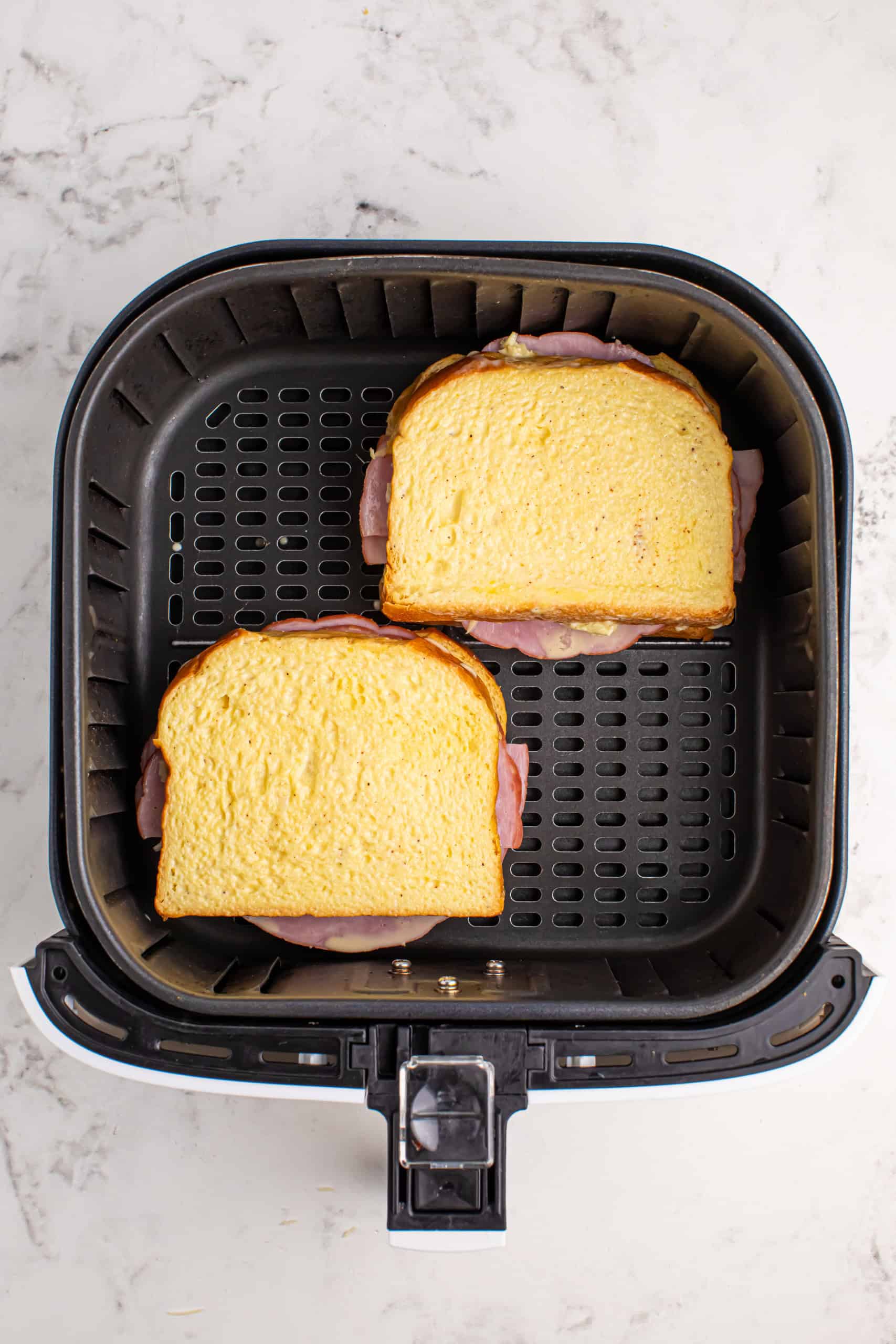 Overhead view of Monte Cristo sandwiches in the air fryer basket.