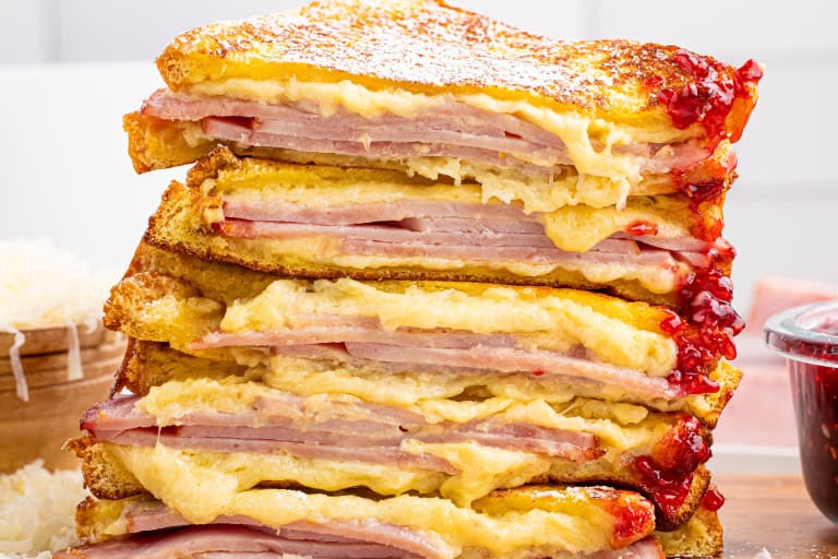 Monte cristo sandwiches cut in half with melty cheese and raspberry preserves dripping down the side.