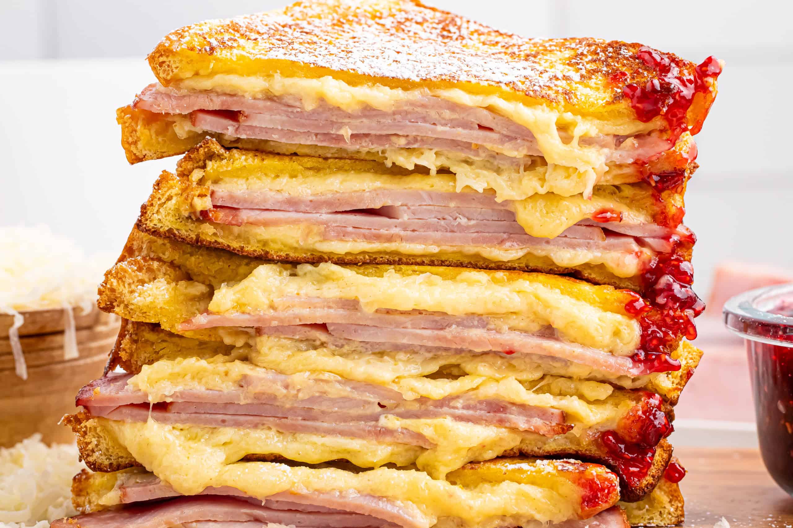 Monte cristo sandwiches cut in half with melty cheese and raspberry preserves dripping down the side.