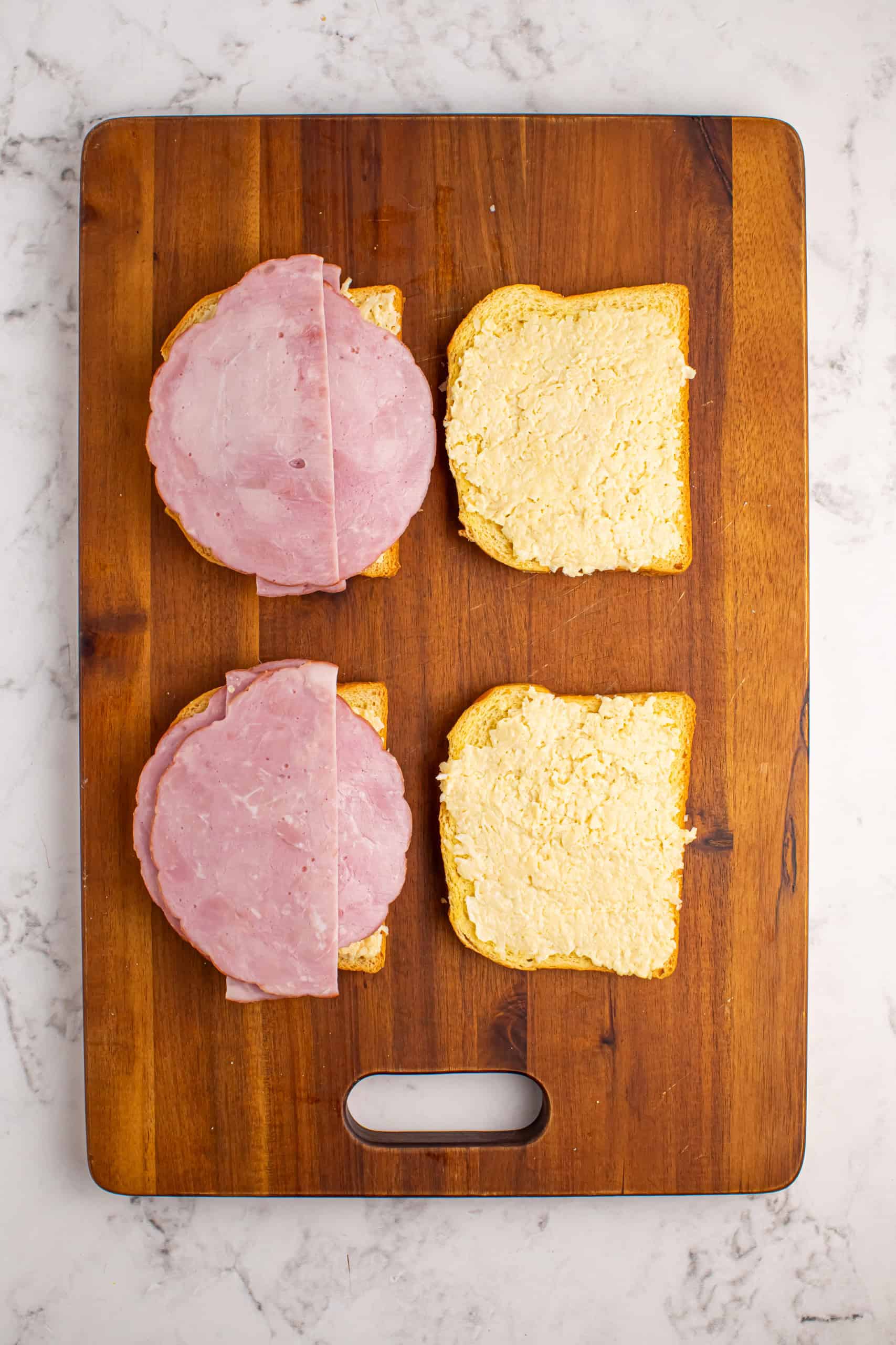 Layering ham and cheese on brioche bread.