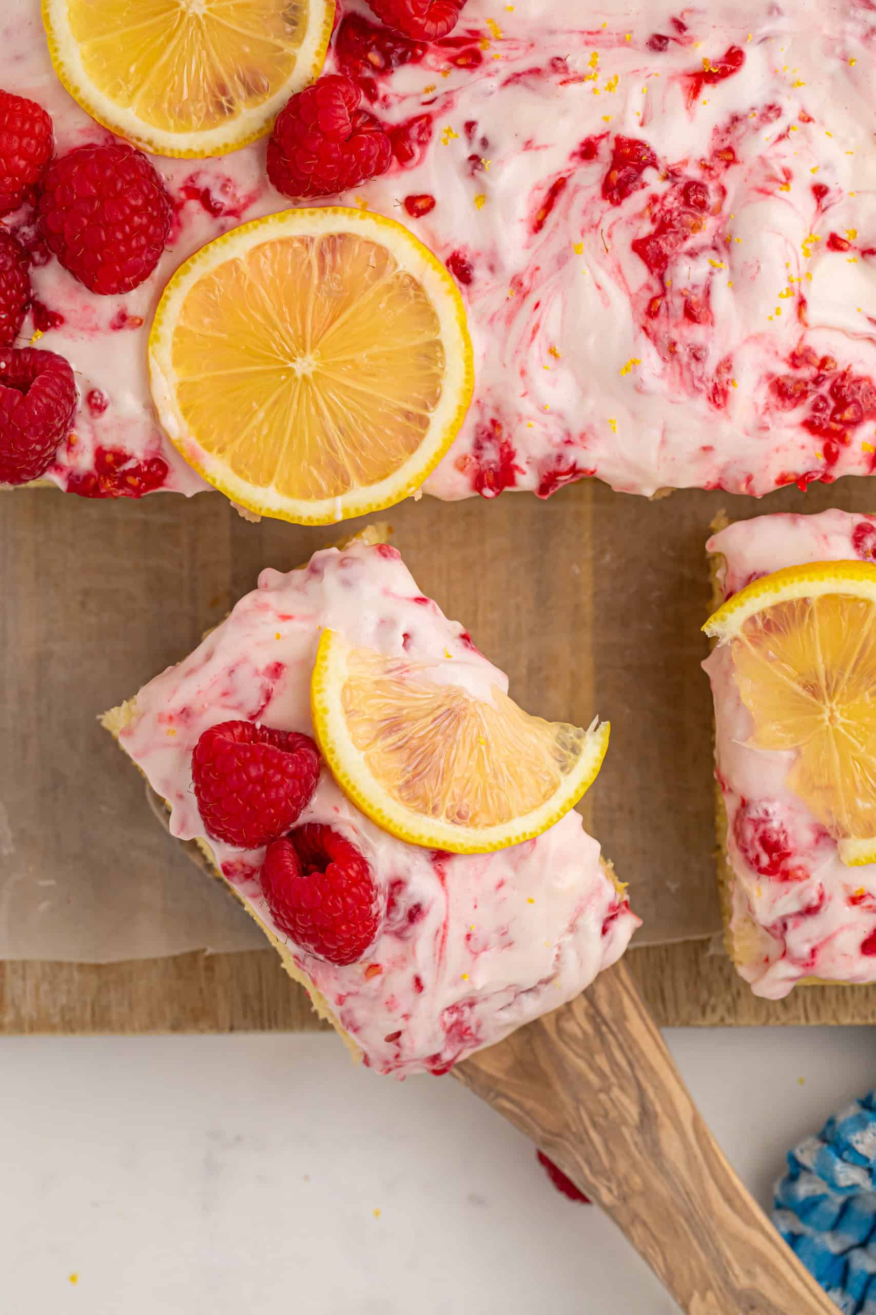Overhead view of raspberry lemon cake and slice of cake on a spatula.