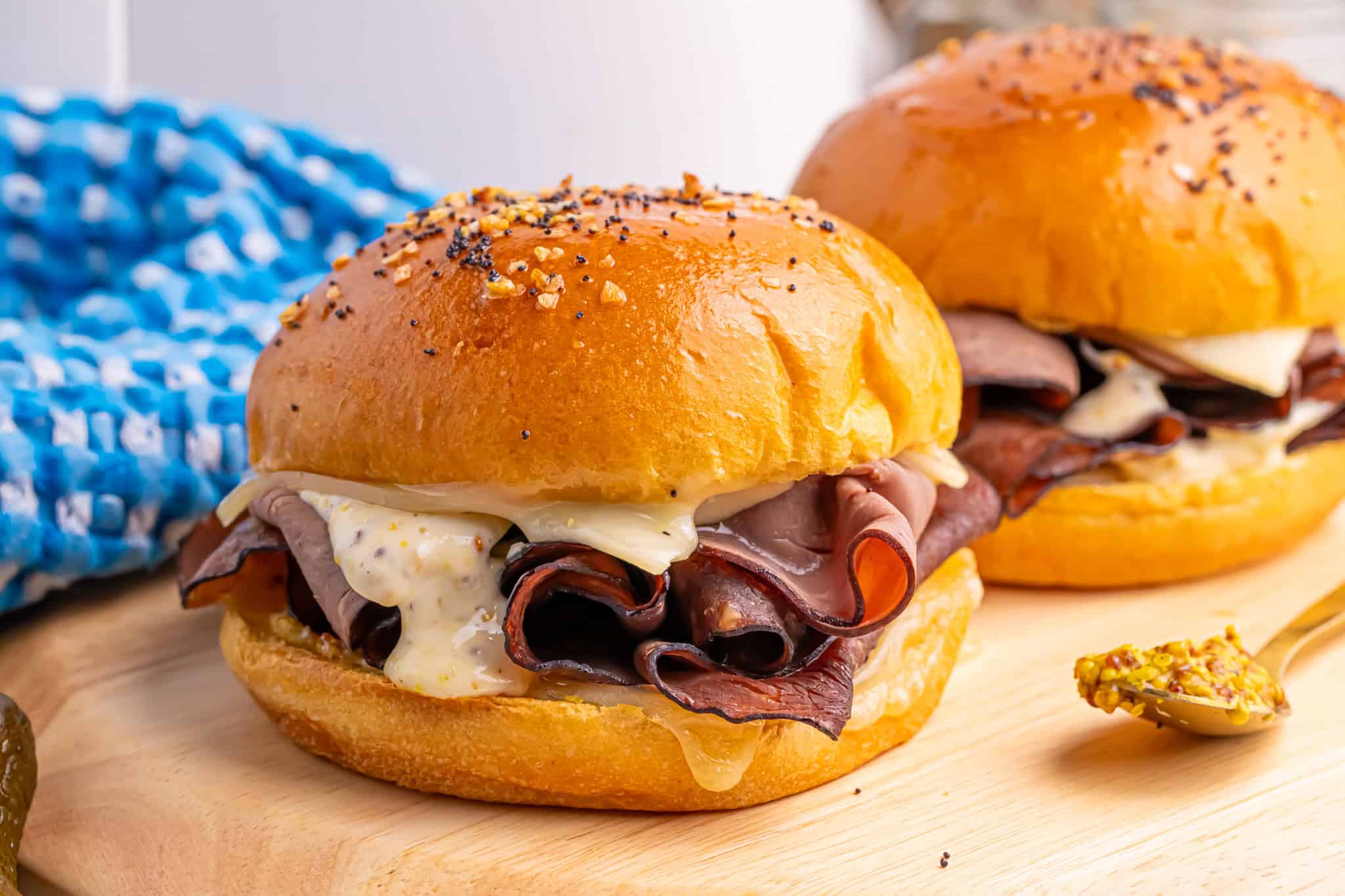 Two Air Fryer Beef and Swiss Cheese Sandwichs on a cutting board.